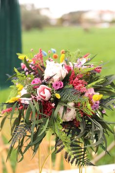 a bouquet of flowers sitting on top of a wooden table next to a green field