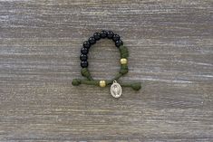 Kid's Army Green and Black Rosary Bracelet featuring black beads, olive Our Father bead, and a small Miraculous Medal; handmade with tradition and faith in mind. Casual Black Friendship Bracelets With 8mm Beads, Casual Black Paracord Bracelet, Adjustable Black Paracord Braided Bracelet, Adjustable Black Paracord Jewelry, Adjustable Black Friendship Bracelets With 8mm Beads, Adjustable Handmade Black Rosary Bracelet, Mary Prayers, Hail Mary Prayer, Paracord Rope