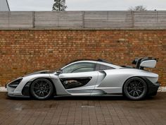 a silver sports car parked in front of a brick wall