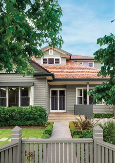 a gray house with white trim and brown roof