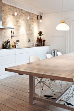 a dining room table and chairs in front of a brick wall with lights on it