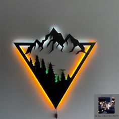 there is a neon sign with mountains and trees in the shape of a triangle on it