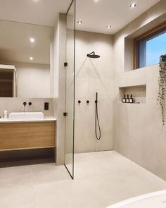 a bathroom with a walk in shower next to a white sink and tub under a window