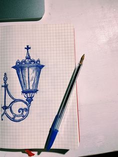 a pen is sitting on top of a notebook with a drawing of a street lamp