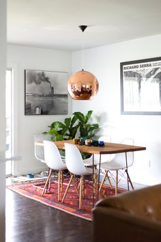 a dining room table with white chairs and a large potted plant