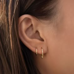 a woman's ear is shown with two small diamond hoops on the side