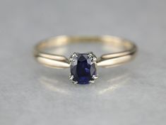 a ring with a blue sapphire stone on the side and two white diamonds around it