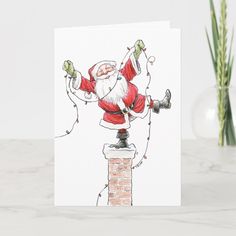 a christmas card with a drawing of santa claus on top of a brick chimney and lights