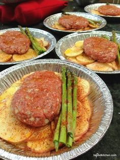 an image of some food that is in tin foil pans on the table with asparagus