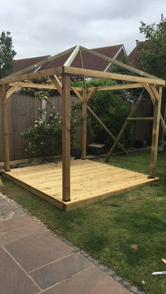 a wooden gazebo sitting on top of a lush green field