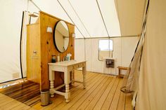 the inside of a tent with wood flooring and white walls, including a sink