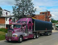 a purple semi truck driving down the road