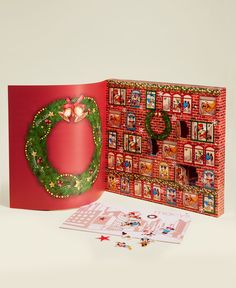 an open christmas card with a wreath on the front, and a red box behind it