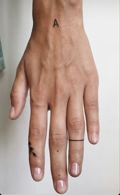 a person's hand with a small tattoo on the left side of their finger