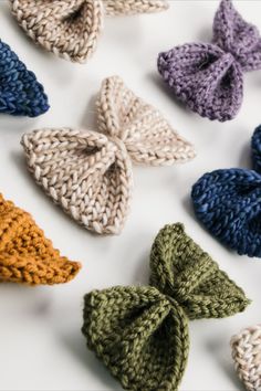 many different colored knitted bows on a white surface