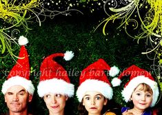 three people wearing santa hats laying in the grass