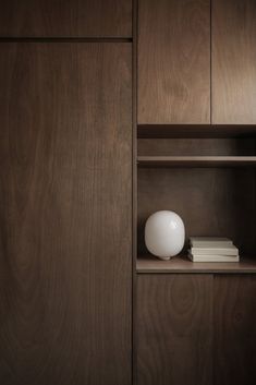 a white vase sitting on top of a wooden shelf next to books in a bookcase