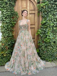 a woman standing in front of a wooden door wearing a dress with flowers on it