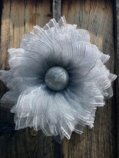 a large white flower on top of a wooden door handle with netting around the petals