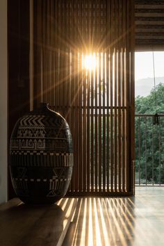 a large vase sitting on top of a wooden table in front of a sliding glass door