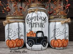 three painted mason jars with pumpkins and a black truck on them, sitting next to each other