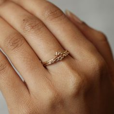 a woman's hand wearing a gold ring with three diamonds on the middle finger