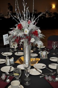 a centerpiece with flowers and silverware sits on a black table cloth at an event