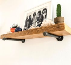 a wooden shelf with some plants and pictures on it