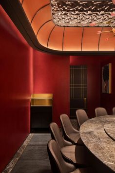 a large conference room with red walls and chairs around a round table in the center