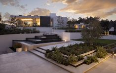 an outdoor area with stairs, trees and plants on the side of the house at dusk