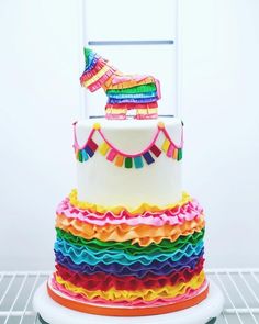 a multicolored cake with a horse decoration on top is sitting on a rack