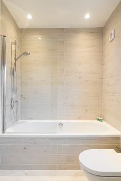 a white toilet sitting next to a bath tub in a bathroom under a skylight