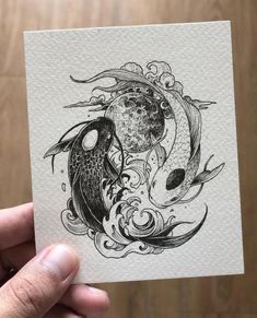 a hand holding up a card with two fish on it