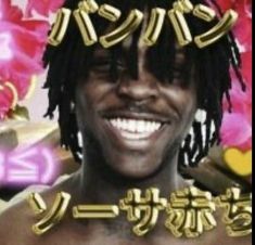 a man with dreadlocks smiling in front of pink and gold decorations on his head