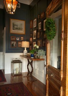 a living room with pictures on the wall and a table in front of an open doorway