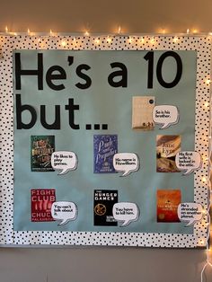 a bulletin board that has been decorated with various books and lights on the wall above it