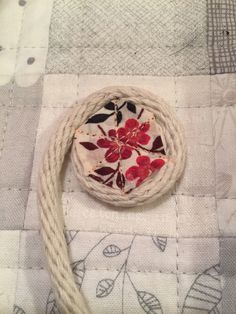 a piece of cloth with red flowers on it sitting on a white tablecloth next to a rope