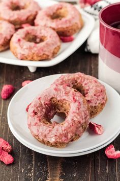 there are two donuts on the plate with pink icing and raspberries