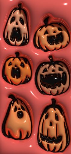 four pumpkins with faces painted on them are in a pink tray, one is orange and the other is black