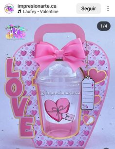 a pink heart shaped box with a bottle in it and a bow on the top