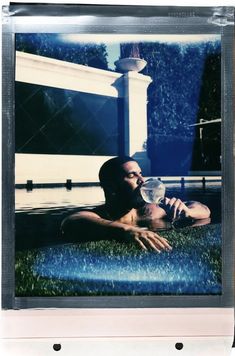 a man laying on the ground drinking water from a glass in front of his face