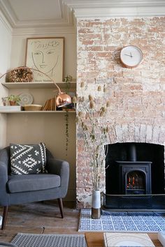 a living room filled with furniture and a fire place in front of a brick wall