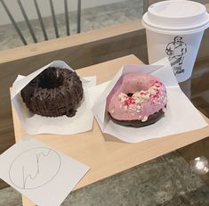 two doughnuts and a cup of coffee on a table with paper napkins