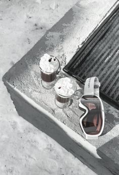 two cups of coffee sitting on top of a grate next to an object that looks like a helmet