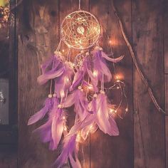 a purple dream catcher with lights hanging from it's side on a wooden wall