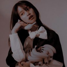 a woman in a black and white outfit holding bananas up to her face while wearing a bow tie