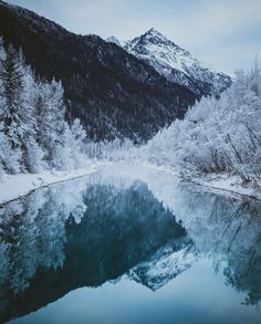 a lake surrounded by snow covered mountains and trees