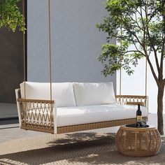 a white couch sitting on top of a wooden swing chair next to a small tree