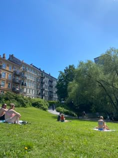 some people are sitting on the grass in front of buildings