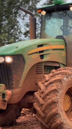 a green tractor is driving through the mud